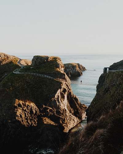 cliff person on hanging bridge during daytime outdoors